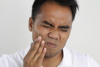 man holding his mouth in need of an emergency dentist