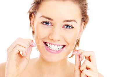 woman smiling while flossing her teeth